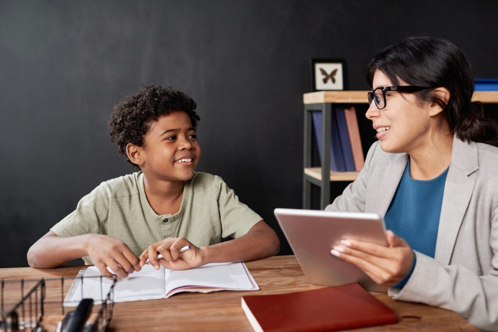 Smiling teacher assisting boy with homework